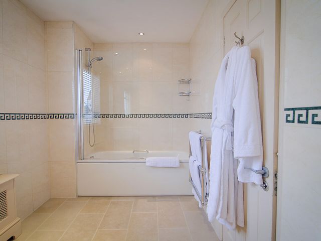 Spacious bathroom with bath, shower and white robe in the Beaufort Hotel
