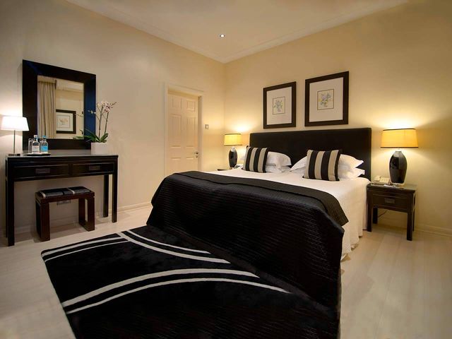 Deluxe Room with fire place, large black rug and large double bed in the Beaufort Hotel